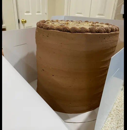 Tall chocolate layer cake in an open bakery box