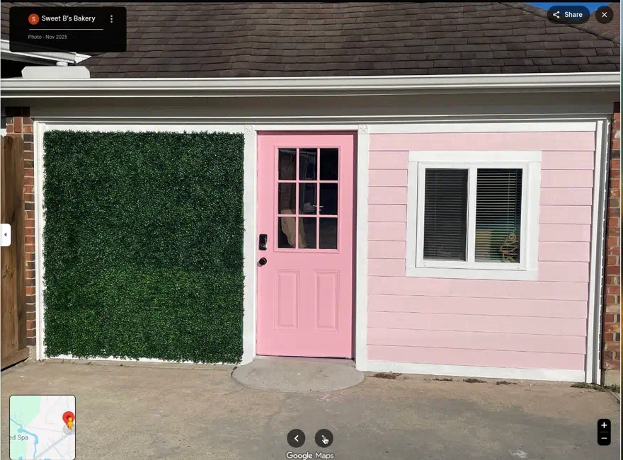 Sweet B's Bakery storefront with pink door and green hedge wall