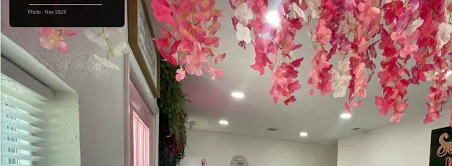 Interior of Sweet B's Bakery: teal chairs, pink door, hanging florals, and the display case